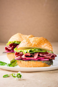 Ready-to-eat hamburger with pastrami, vegetables and basil on a plate on craft paper