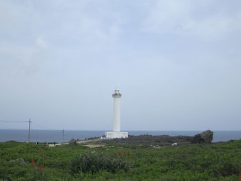 Lighthouse by sea against sky