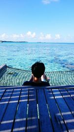 Rear view of woman at swimming pool against sky