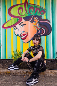 Portrait of smiling girl against graffiti wall