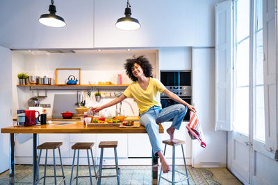 Woman sitting on table in kitchen
