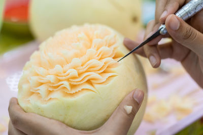 Cropped hands carving cantaloupe