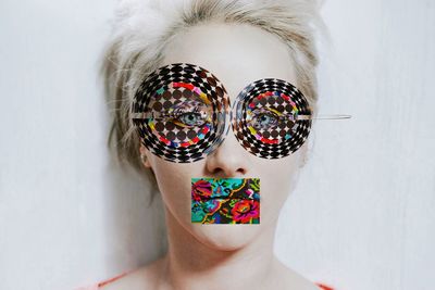 Digital composite image of woman with colorful pattern on face against wall