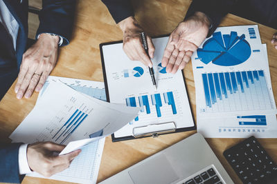 Midsection of businessman and colleague working on graph at office