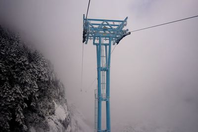 Low angle view of communications tower against sky during winter