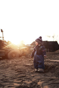 Full length of baby boy standing on land against clear sky during sunset