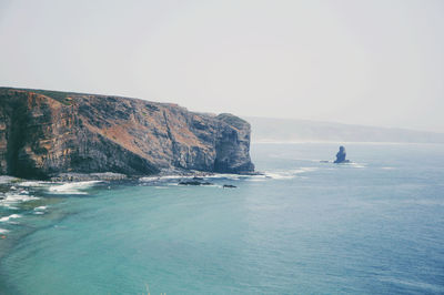 Scenic view of sea and rocks against clear sky