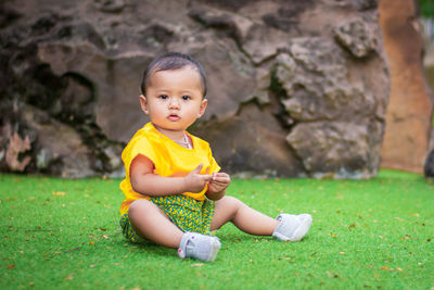 Full length of the cute boy sitting on the field