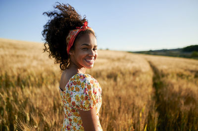 Portrait of a smiling young woman standing on field