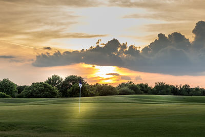 Scenic view of a golf course against sky during sunset