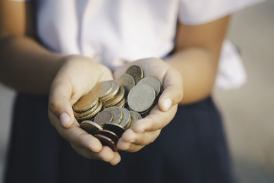 Midsection of girl holding coins outdoors