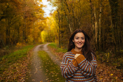 Portrait of smiling young woman standing in forest