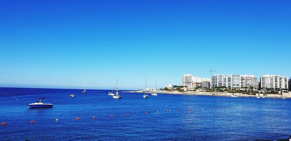 Sailboats in sea against clear blue sky