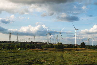 Windmills on field against sky