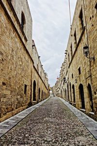 Cobblestone street amidst buildings against sky