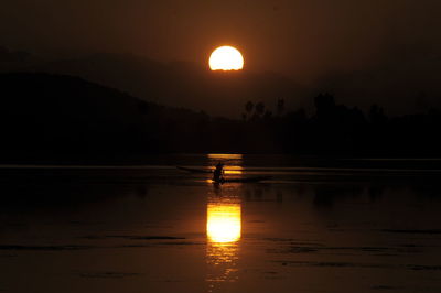 Silhouette tree by lake against sky during sunset