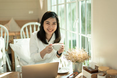 Young woman holding coffee cup on table