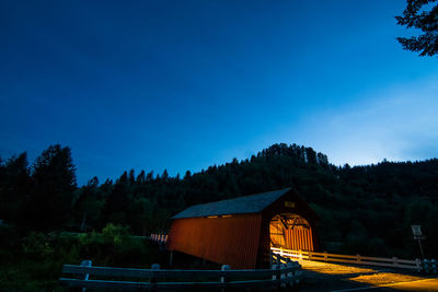 Illuminated covered footbridge against clear sky at dusk