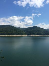 Scenic view of lake by mountains against sky