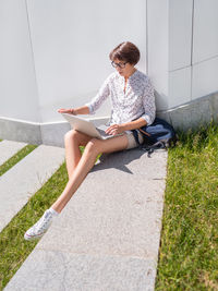 Side view of woman sitting on footpath