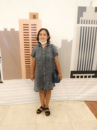 Portrait of smiling woman standing against wall