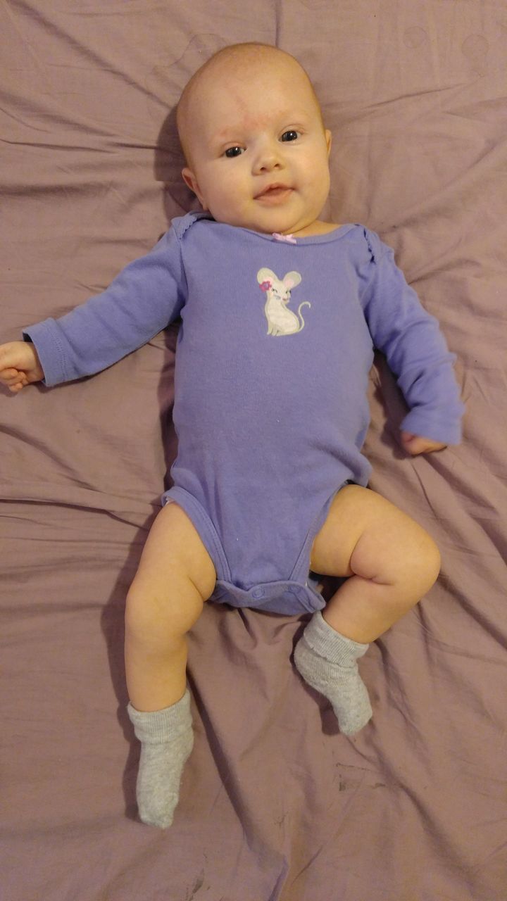 baby, indoors, full length, innocence, cute, high angle view, babyhood, real people, childhood, hardwood floor, lying on back, home interior, one person, looking at camera, sitting, portrait, day, close-up, people