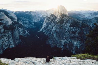 Rear view of man sitting by rocky mountains at yosemite national park