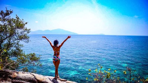 Rear view of woman standing in sea against sky