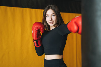 Young brunette woman in black wear engaged boxing training in fitness club