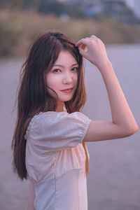 Portrait of young woman standing at beach