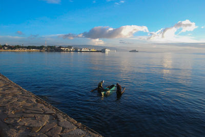 Rear view of people boating in river