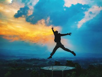 Silhouette man jumping over land against sky during sunset