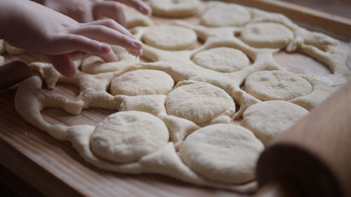 Cropped hands of kid on dough