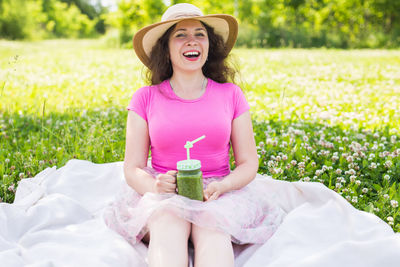 Portrait of a smiling young woman sitting on field