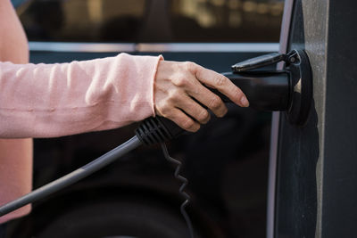 Woman holding electric charger at charging station
