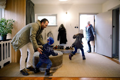 Playful siblings with parents in mudroom at home