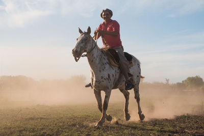 Portrait of man riding horse with a lot of dust