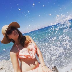 Young woman wearing sunglasses on beach against clear sky