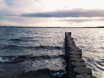 Pier on sea against cloudy sky