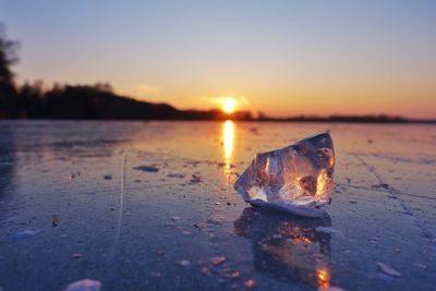 Close-up of leaf on water against sky during sunset