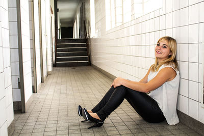 Portrait of smiling woman sitting on tiled floor