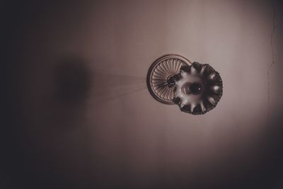 Close-up of electric lamp hanging on wall at home