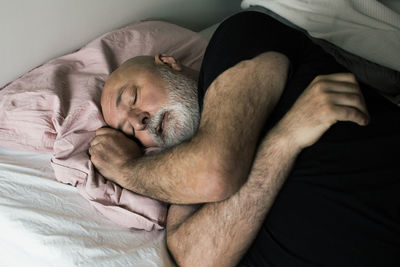 Exhausted mature man lying down on bed at home