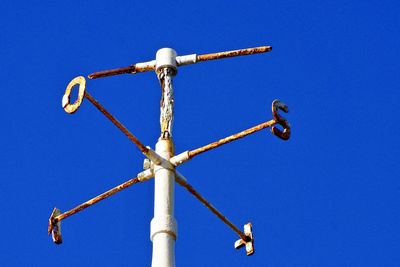 Low angle view of weather vane against blue sky