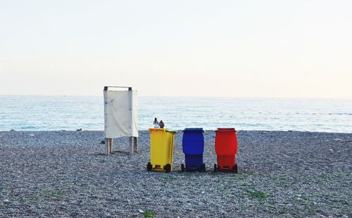 Rear view of deck chairs on beach against clear sky