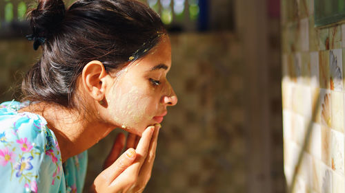 A beautiful woman is washing facial mask in bathroom after applying face mask.