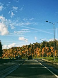 Road by trees against sky