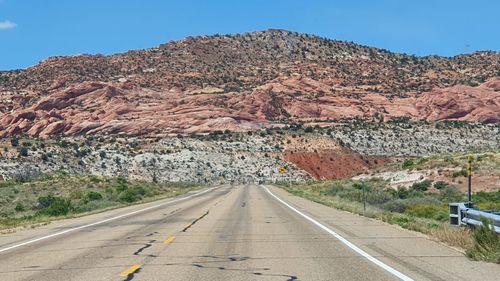 Road leading towards mountains against clear sky