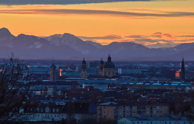 Townscape by mountains against sky at sunset