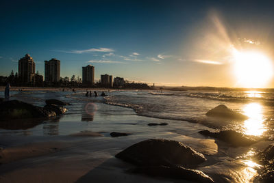 Scenic view of sea by buildings against sky during sunset